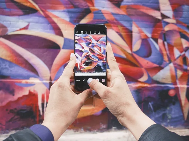 Smartphone taking a picture of a colorful wall graffiti