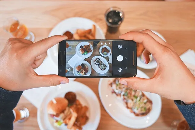 Smartphone taking a picture of four plated food